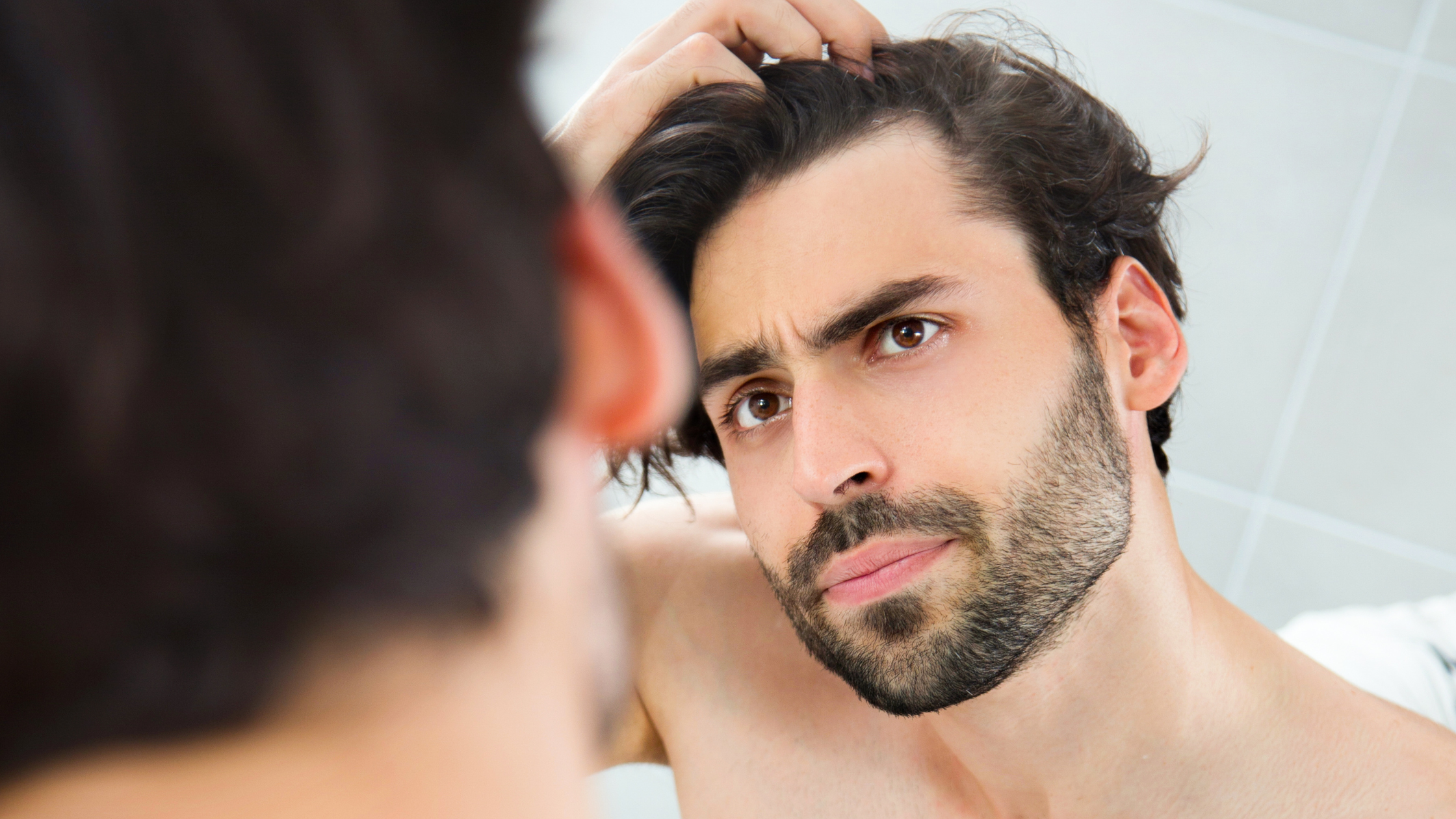 Homem se olhando no espelho após usar Produtos para Controlar a Queda de Cabelo